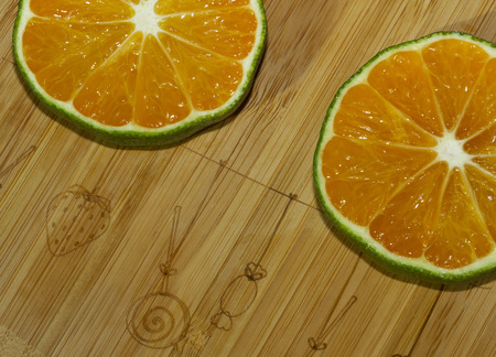 Slices of mandarin and lime on the cutting boardの写真素材
