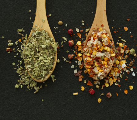 Two spoons with spices on the black backgroundの写真素材