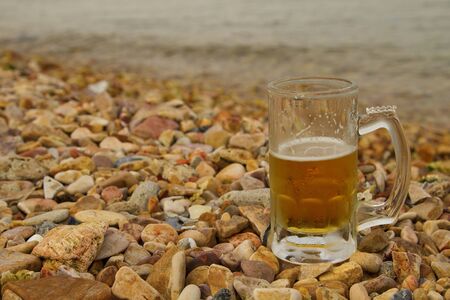 Glass of beer on the pebble beachの写真素材