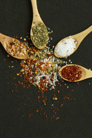 Four spoons with spices on the black background with copy spaceの写真素材