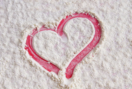 Red heart on flour background, top viewの写真素材