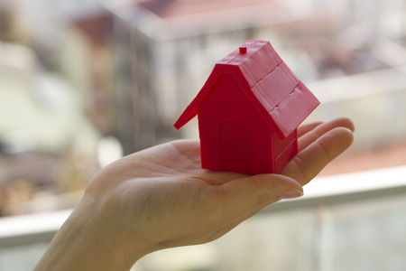 Small red house in the woman's hands の写真素材