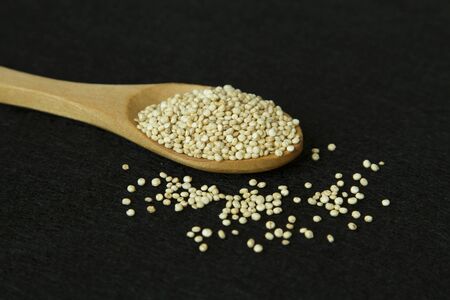 Wood spoon with quinoa on black backgroundの写真素材