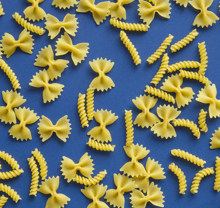 Pasta bow and  spiral shape on blue background の写真素材