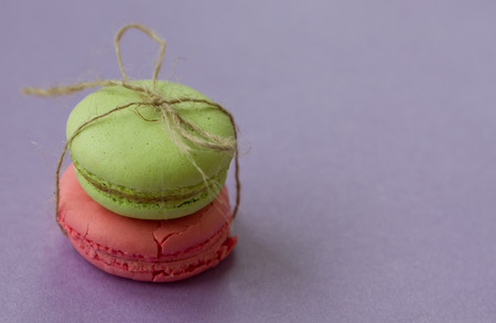 Two macaroons with bow from natural rope on purple background with copy spaceの写真素材
