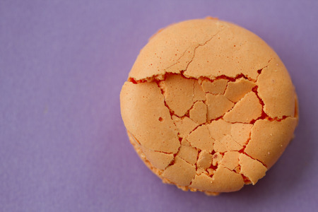 One orange crashed  macaroon on purple background top voew with copy spaceの写真素材