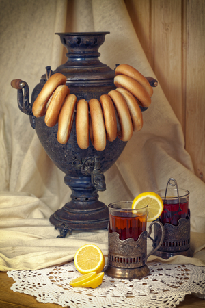 Russian samovar, tea with lemon in faceted glasses with cup holders and bublik. Tinted photo in vintage style.の写真素材