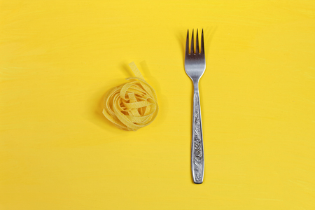 Close up of a raw dry italian pasta fettuccine on bright yellow background. Shooting with bold colorの写真素材