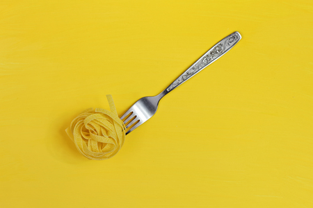 Close up of a raw dry italian pasta fettuccine on a bright yellow background. Shooting with bold colorの写真素材