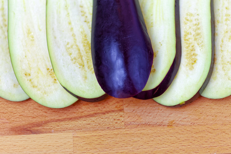 Aubergine or eggplant with slices on wooden backgroundの写真素材