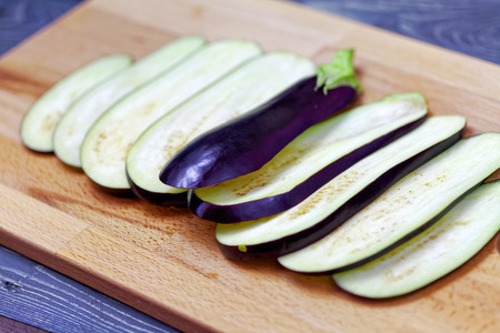 Aubergine or eggplant with slices on wooden backgroundの写真素材