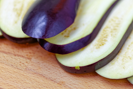 Aubergine or eggplant with slices on wooden backgroundの写真素材