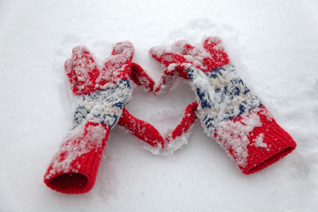 Winter gloves make the shape of a heart on a snowの写真素材