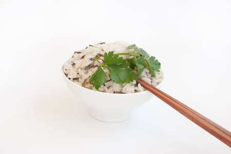 White ceramic bowl with boiled rice and wooden chopsticks isolated on whiteの写真素材