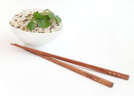 White ceramic bowl with boiled rice and wooden chopsticks isolated on whiteの写真素材