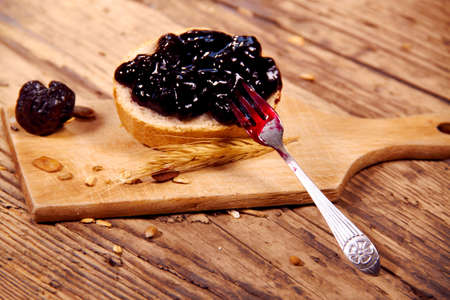 Plum jam with bread on wooden plankの写真素材