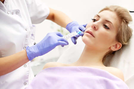 Beautiful woman gets an injection in her faceの写真素材