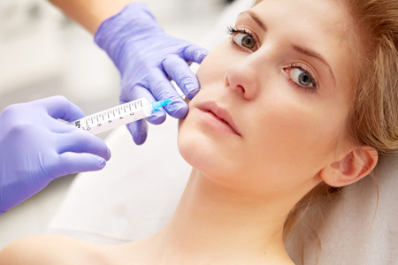 Beautiful woman gets an injection in her faceの写真素材