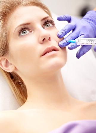 Beautiful woman gets an injection in her faceの写真素材