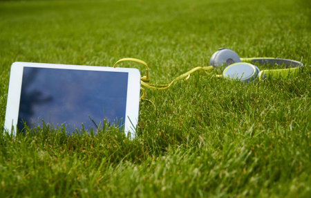 white tablet and headphones lying on the grassの写真素材