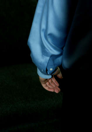 business man with his arm hanging in the darknessの写真素材