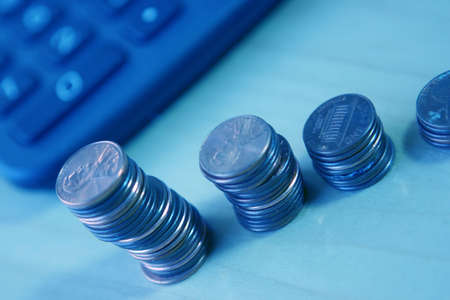 Table with calculator and coins stacked in a rowの写真素材