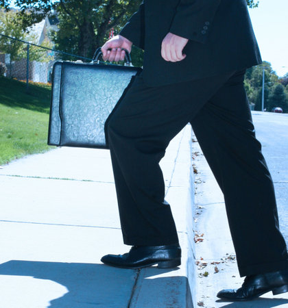 Business man takes a step up onto the sidewalkの写真素材