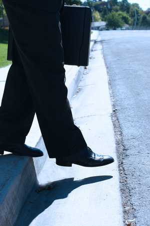 Business man takes a step into the street
