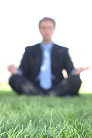 Business man sits on the green grass and meditatesの写真素材