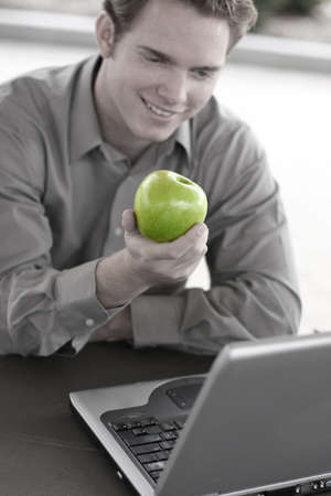 Business man holds a green apple in hand at lunchの写真素材