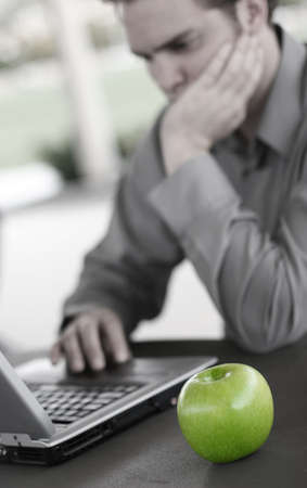 Business man works on his laptop with a green appleの写真素材