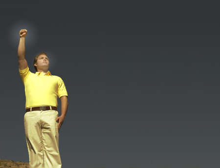 Man standing with his fist raised in front of the blue sky の写真素材