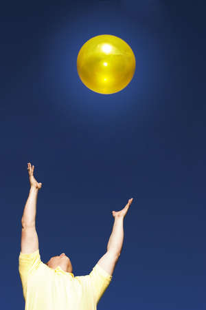 Man in a yellow shirt with his hands out worshipping the sunの写真素材