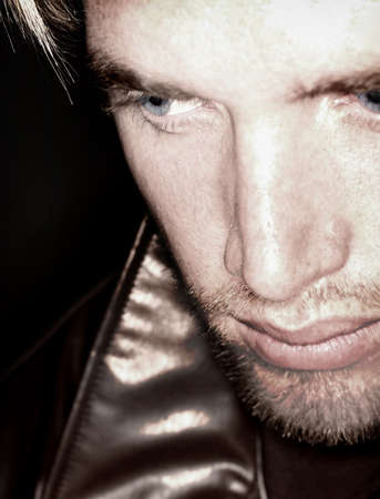 Blond hair and blue eye man looking off and down into the distance while wearing a leather jacketの写真素材