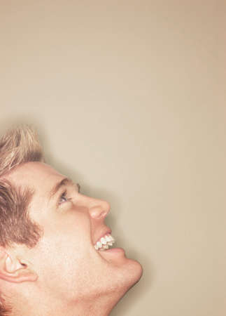 Business Man with blond hair and blue eyes and big smile looking off into the air against tan backgroundの写真素材