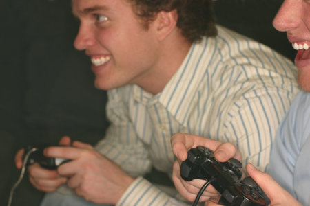 Two young men are playing video games side by side