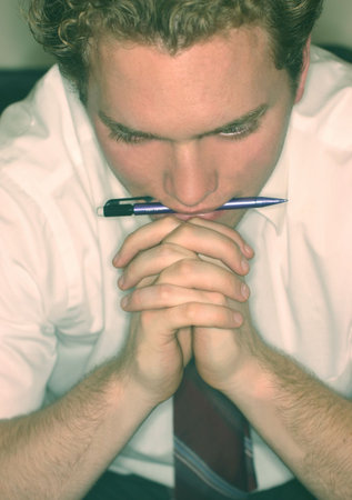 Business man wearing white shirt and red tie is biting down on pencil の写真素材