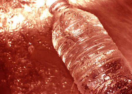 Water bottle in the middle of a rush of red colored waterの写真素材