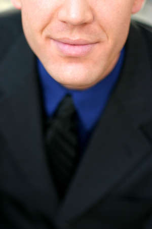 Business man with black suit, black tie, and blue shirt is almost smilingの写真素材