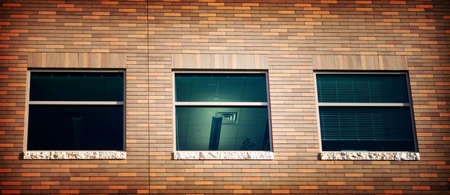 Three windows in a brick building with the middle room lit upの写真素材