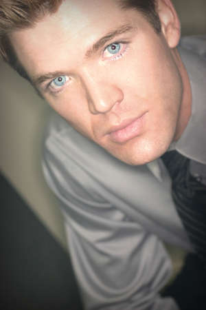 Blond hair, blue eye business man is wearing gray shirt and is looking directly at youの写真素材