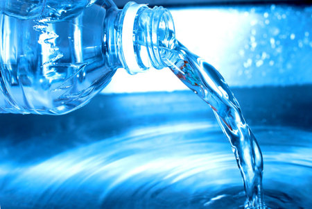Water from a water bottle is being poured out into a metal container,