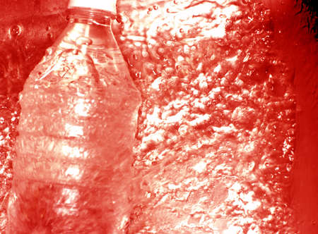 Red colored water is rushing around a water bottleの写真素材
