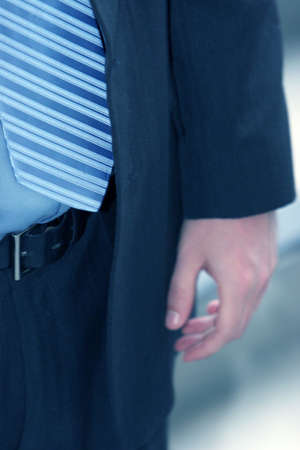 close-up of blue striped tie, blue shirt, and dark blue suit with man's handの写真素材