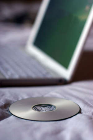 Laptop with CD on bedの写真素材