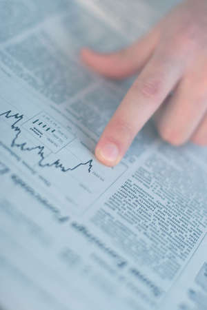 Finger pointing to the chart in the business section of the newspaperの写真素材