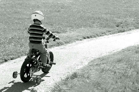 Small boy is prepared to ride his bike as he sets out on a path that leads out of the pictureの写真素材