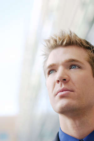 Blond hair blue eye business men is dressed in blue shirt and black suit, looks off into the distanceの写真素材