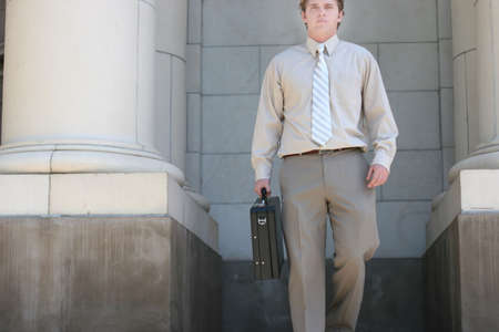 Lawyer is walking down the steps of the courthouse towards you with a black briefcase in his handの写真素材