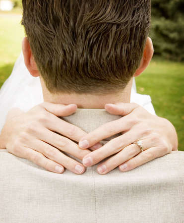 Bride puts hands around the back of the grooms neck in the middle of a parkの写真素材